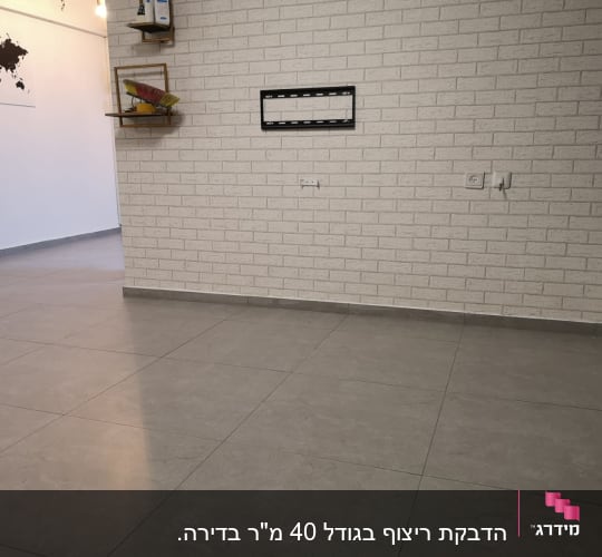 קיר לבנים עם מתקן לטלוויזיה, רצפת אריחים אפורה